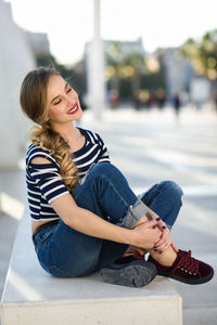 Full length of beautiful young woman sitting on marble