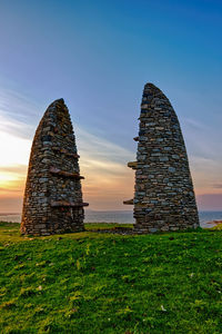 Stone wall on field against sky during sunset