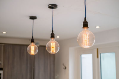 Low angle view of illuminated light bulbs hanging from ceiling