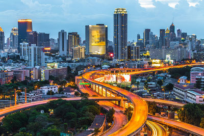 High angle view of light trails on road amidst buildings against sky