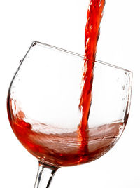 Close-up of red wine glass against white background