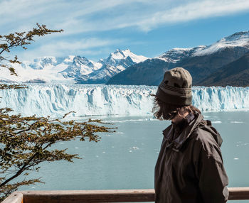 Woman standing by lake against mountains during winter
