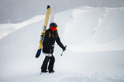 Sports woman skier climbs uphill to the top to quickly go down the mountain, off the track