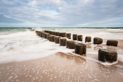 Wooden posts on beach against sky