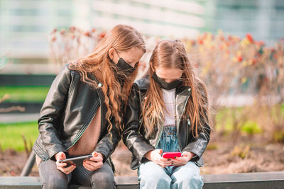Full length of woman using mobile phone outdoors