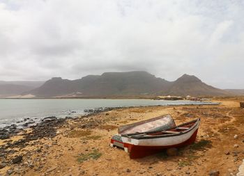 Boat moored on beach against sky