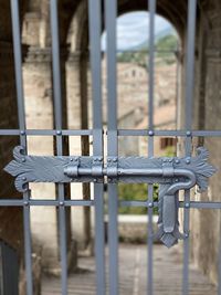 Electric lamp hanging on metal gate against building