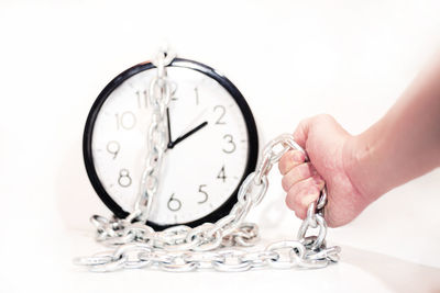 Close-up of woman hand with clock against white background