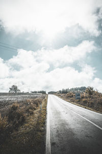 Road amidst field against sky