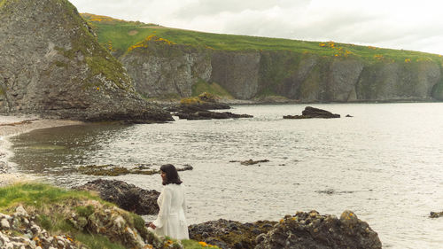 Rear view of woman standing at beach