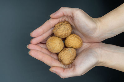 Close-up of human hand holding bread against black background