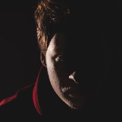 Close-up portrait of young man against black background