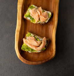 Toast with cream cheese, avocado and salmon on a wooden plate, dark background