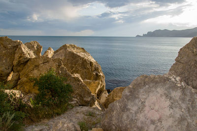 Rocks on shore by sea against sky