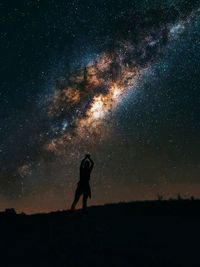 Silhouette woman standing on field against sky at night