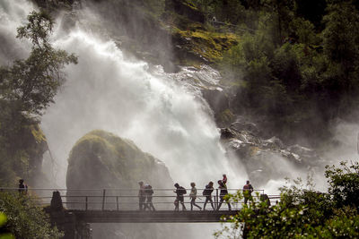 Panoramic view of people looking at waterfall