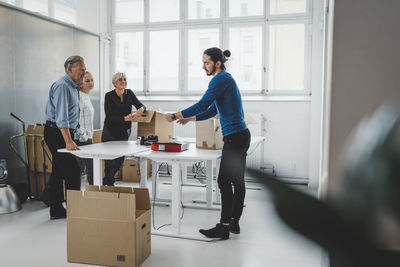 Multi-ethnic male and female business people unpacking cardboard boxes in new office