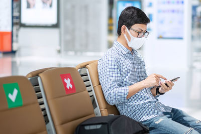 Young man using mobile phone while sitting in airport
