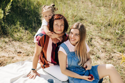 A grandmother and her two granddaughters have a picnic in nature, spend time together on weekends