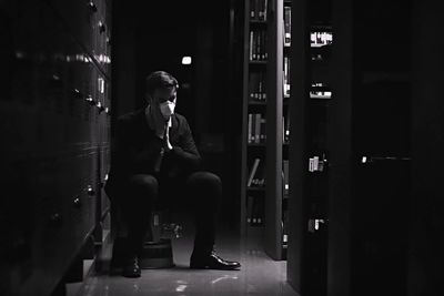 Full length of young man sitting at entrance of building