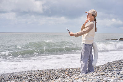 Rear view of woman standing at beach against sky