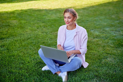 Woman using phone while sitting on grass