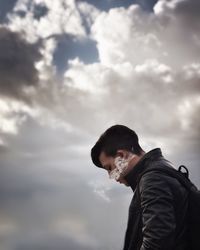 Side view of young man standing against sky