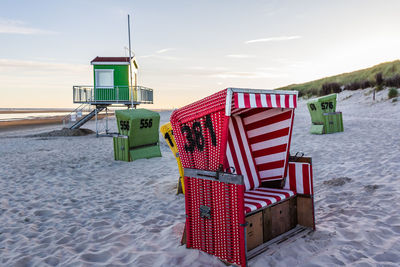 Hooded chairs on beach against sky