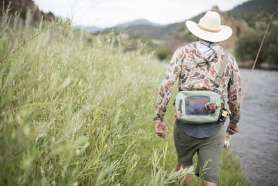 A fly fisherman walking up the banks of the colorado river.