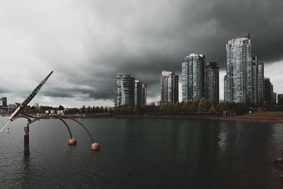 Buildings by river against sky