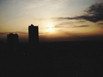 Silhouette cityscape against sky during sunset