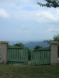 Built structure on field by sea against sky