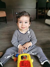Portrait of smiling baby boy sitting on floor at home