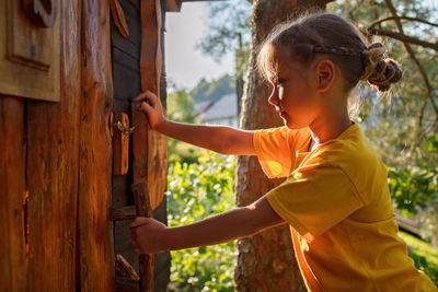 Side view of young woman standing against trees