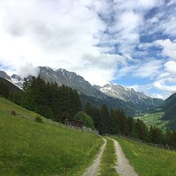 Road amidst green landscape and mountains against sky