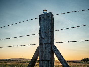 Low angle view of barbed wire fence against sky