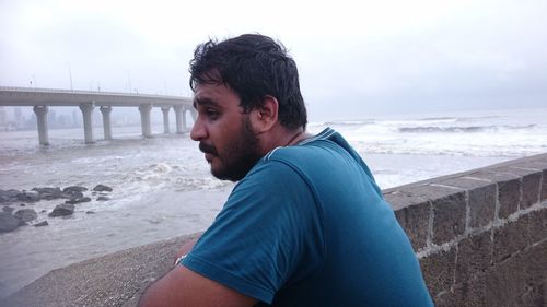 Thoughtful man standing by retaining wall with bandraworli sea link in background