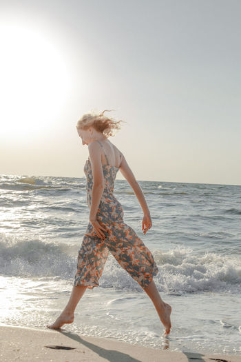 Woman wading in sea against clear sky