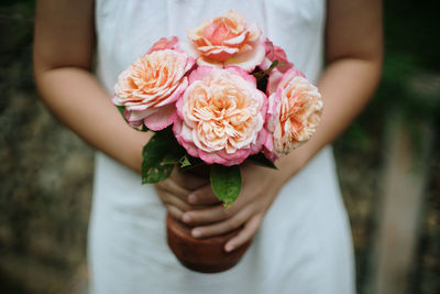 Close-up of woman holding pink rose flower