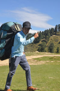  young guy smiling, looking at camera while walking with carrying parachute backpack in the mountain 