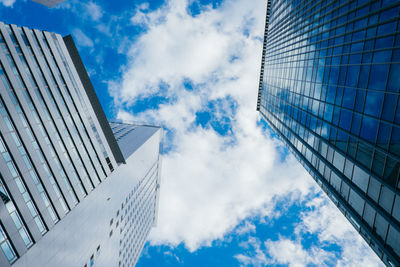 Directly below shot of modern buildings against cloudy sky