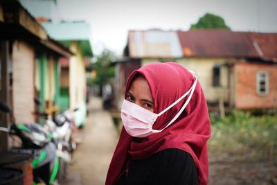 Portrait of young woman wearing sunglasses against built structure