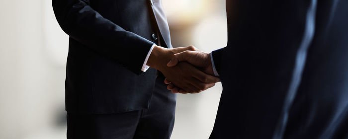 Midsection of businessman standing against black background