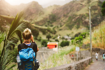 Rear view of woman photographing standing against mountains