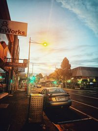 Cars on street in city against sky during sunset