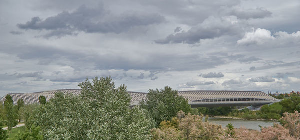 View of trees and buildings against cloudy sky