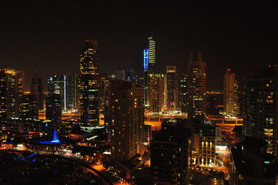 Illuminated modern buildings in city against sky at night