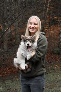 Portrait of a dog and young woman standing in a forest