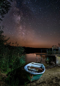 Boat moored on land against sky at night