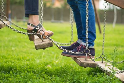 Low section of couple standing on playground equipment